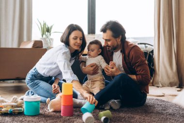 Mutlu anne ve babanın portresi, evdeki rahat odada erkek çocuklarıyla oynaşıyor. Ebeveynlik, aile, aşk ve bakım kavramı