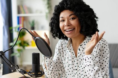 Genç bir kadın mikrofona konuşuyor ve sesi kaydediyor, çevrimiçi izleyicileri için içerik yaratıyor.