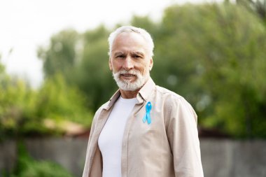 Açık mavi kurdele takan kendinden emin bir adamın portresi prostat kanseri farkındalığını gösteriyor.