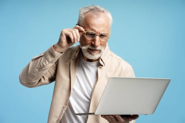 Diz üstü bilgisayar kullanan ve gözlük takan olgun bir adam, canlı mavi bir arkaplan karşısında iş konularıyla ilgili endişelerini dile getiriyor