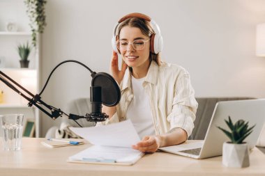 Podcaster ses içeriği yaratıyor, mikrofona konuşuyor ve notları okuyor, evden çalışıyor. Podcast konsepti