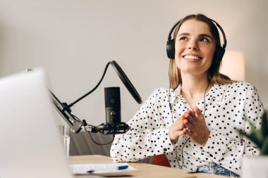 Genç ve mutlu bayan radyo sunucusu mikrofonla konuşuyor, stüdyoda podcast yapıyor. Çevrimiçi iletişim kavramı