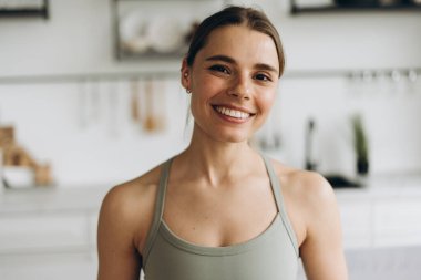 Mutfakta spor sutyen giyen gülümseyen kadın portresi kameraya bakıyor, manken pozu veriyor. Reklam kavramı