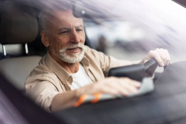 Gülümseyen son sınıf öğrencisi, arabasının konsolunu mikrofiber bezle temizlerken, rahat ve temiz bir yolculukta aracının keyfini çıkarıyor. Araba bakımı konsepti