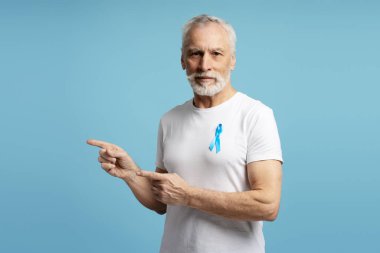 Mavi kurdele takan son sınıf öğrencisi mavi arka planda iki işaret parmağıyla prostat kanseri farkındalığını, kolon kanseri farkındalığını ve diğerlerini destekliyor. Reklam kavramı