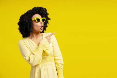 Güneş gözlüğü takan, parmakla, modayla, güzellikle, duyguyla mekanı gösteren afro-amerikan kadın portresi.
