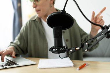 İçerik oluşturucu ses içeriğini profesyonel bir mikrofon ile kaydediyor ve dizüstü bilgisayar kullanırken hareket ediyor