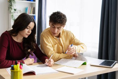 İki konsantre öğrenci evde birlikte öğreniyor, notlar yazıyor ve üniversite sınavına hazırlanıyor.