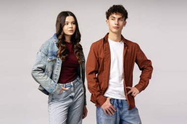 Gri arka planda elleri kalçalarında rahat pozlar veren, rahat kıyafetler giyen modaya uygun gençler, gençlik tarzı ve tavırları yayıyorlar.