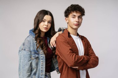 Kollarını kavuşturarak poz veren kendinden emin öğrenciler, gençlik enerjilerini ve akademik isteklerini tarafsız bir arkaplanda sergiliyorlar.