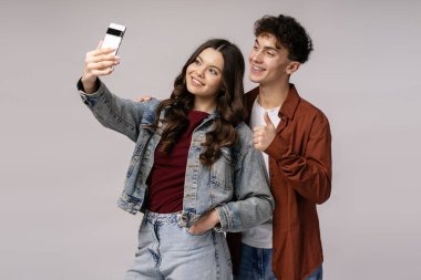 Gülümseyen gençler akıllı telefonlarıyla selfie çekiyorlar, başparmaklarını gösteriyorlar, pozitifliklerini ve neşelerini gösteriyorlar.