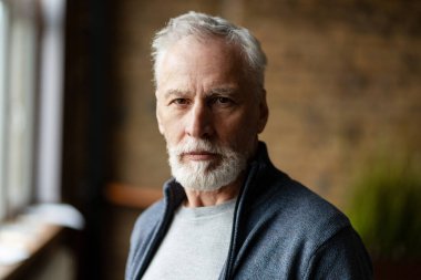 Beyaz saçlı, sakallı, ciddi bir son sınıf öğrencisinin portresi.