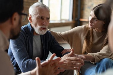 Grup terapisi sırasında sorunlarından bahseden son sınıf öğrencisi endişeli, insanlar onu dinliyor ve destekliyor.