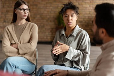 Hastalar grup terapisi sırasında rahat bir odada psikologla sorunlarını tartışıyor.