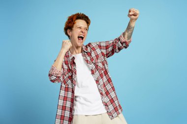 Mavi arka planda çığlıklar atan piercingli neşeli genç kadın portresi. İnsan yüz duyguları konsepti