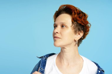 Kot ceketli, sakin bir ifadeyle, mavi üzerine izole edilmiş, fotokopi odasına bakan şık bir genç kadın. Bireysellik, çeşitlilik ve kendini ifade etme kavramı