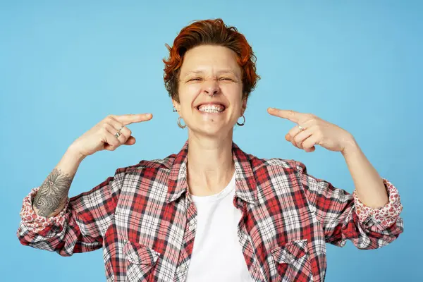 Gülümseyen, beyaz dişlerini gösteren, kameraya bakan, piercing takan neşeli kadının portresi. Bireysellik, çeşitlilik ve kendini ifade etme kavramı