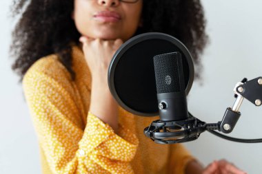 İçerik yaratıcısı, bir mikrofona konuşurken yeni bir podcast bölümü kaydediyor, bir stüdyo ortamında yaratıcılık sürecine dalmış.