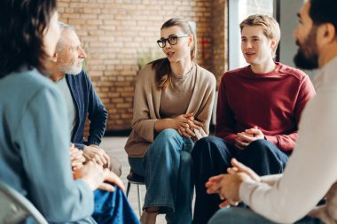Çemberde oturan hastalarla grup terapisi yapan psikoterapist, deneyimleri paylaşıyor ve birbirlerini destekliyor, zihinsel refahı ve iyileşmeyi destekliyor. Psikoloji konsepti