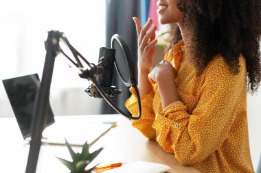 Genç içerik yaratıcısı, stüdyosunda profesyonel bir mikrofon ve dizüstü bilgisayar kullanarak podcast 'ini kaydediyor.