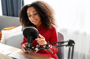 Gülümseyen, güzel bir kadın profesyonel mikrofon kullanarak stüdyoda podcast yapıyor. Çevrimiçi teknoloji kavramı