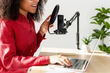 İçerik oluşturucu, dizüstü bilgisayar ve mikrofon kullanarak podcast 'i kaydediyor. Seçici odaklanma, yakın çekim. Profesyonel ekipman konsepti
