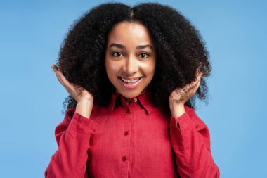 Mavi arka planda gülümseyen ve kameraya bakan heyecanlı genç bir kadının portresi. Saç bakımı konsepti