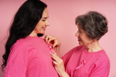 Genç bayanın tişörtüne pembe kurdele takan son sınıf öğrencisi kadın, göğüs kanseri konusunda destek veriyor ve farkındalık yaratıyor.