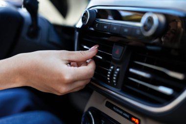 Kadın sürücü hava akımını düzenlemek için havalandırma kontrollerini ayarlıyor ve araçta seyahat ederken rahat bir sıcaklık sağlıyor.