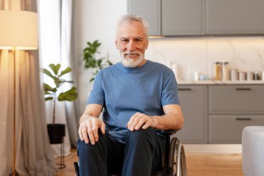 Tekerlekli sandalyeyi kullanan mutlu yaşlı bir adam modern apartmandaki bağımsız yaşam tarzının tadını çıkarıyor. Sağlık hizmeti kavramı