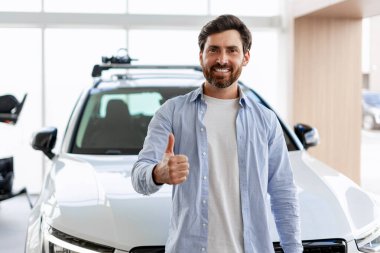 Bir galeriden yeni bir araba aldıktan sonra mutlu bir adam, başarılı yatırımından memnuniyet ve gurur duyuyor.