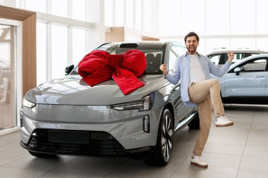 Heyecanlı müşteri, yeni elektrikli araba alımını kutluyor. Hayalindeki arabayı elde etme başarısının tadını çıkarıyor.