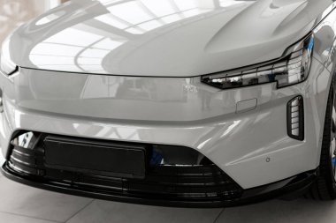 Gösterişli gri elektrikli araç, yenilikçi tasarımını ve gelişmiş teknolojisini parlak bir araba galerisinde sergiliyor.