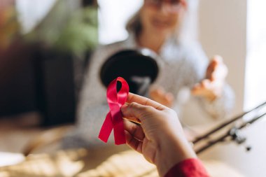 Podcaster önemli sağlık sorunlarını tartışırken, podcast kaydı sırasında göğüs kanseri farkındalığını ve desteğini sembolize eden pembe bir kurdele tutan bir eli kapatın. Sağlık hizmeti kavramı