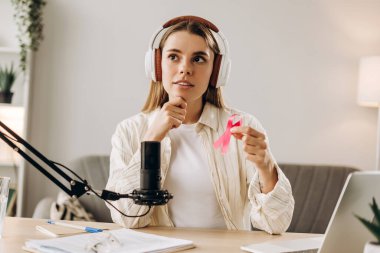 Pembe kurdele tutan kadın radyo sunucusu, stüdyosundaki podcast kaydı sırasında göğüs kanseri farkındalığından bahsediyor. Çevrimiçi iletişim kavramı