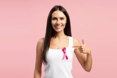Gülümseyen kadın beyaz gömleğine taktığı pembe kurdeleyi göstererek meme kanseri farkındalığını arttırıyor ve hastalıkla mücadeleyi destekliyor. Sağlık hizmeti kavramı