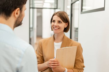 İş kadını elinde bir pano tutarken gülümsüyor iş adamının ofis koridorunda konuşmasını dinliyor, sohbet ediyor ve işle ilgili konuları tartışıyor. Ortaklık kavramı