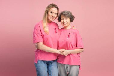 Kız ve anne kucaklaşıyorlar, pembe kurdeleli pembe tişörtler giyiyorlar, meme kanseri farkındalığını destekliyorlar ve hastalığa karşı dayanışma gösteriyorlar. Dövüş kavramı