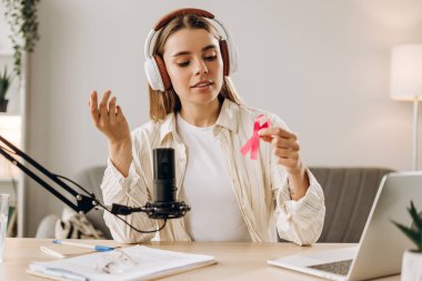 Radyo sunucusu göğüs kanseri farkındalığından bahsediyor. Podcast kaydı sırasında elinde pembe kurdele tutuyor. Sağlık hizmeti kavramı