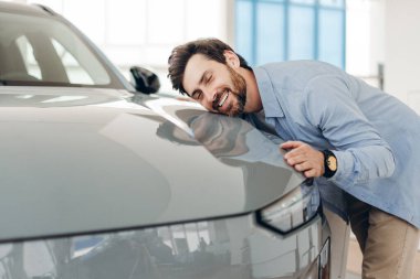 Mutlu müşteri, pozitif Latin sakallı adam bayilikte yeni arabasına sarılıyor. Otomatik satın alma kavramı