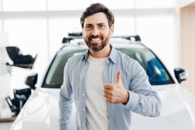 Modern bayilik galerisinde çocuk emniyet koltuğu ile donatılmış yeni bir aile arabası alırken mutlu Latin müşteriler başparmak kaldırıyor, memnuniyet ve başarı saçıyor. Alışveriş konsepti