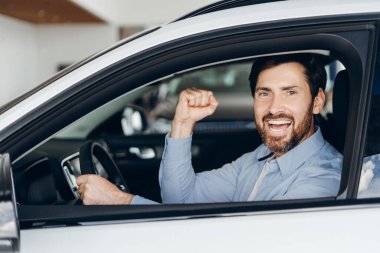 Başarılı işadamı yeni bir araba sürüyor ve başarısını yumruğunu kaldırarak kutluyor, araba galerisinden satın almasından duyduğu heyecan ve memnuniyeti dile getiriyor. Ulaşım kavramı