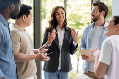 Bir takım toplantısına liderlik eden iş kadını, ofiste bir projeyi tartışan meslektaşlarıyla fikir paylaşımı yapıyor.