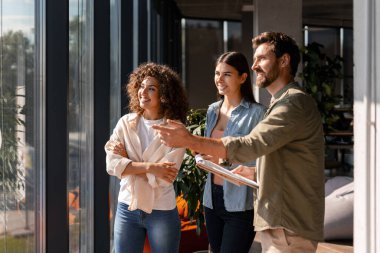 İş dünyası modern ofiste yeni projeyi tartışıyor, yönetici pencerenin dışındaki bir şeyi işaret ediyor
