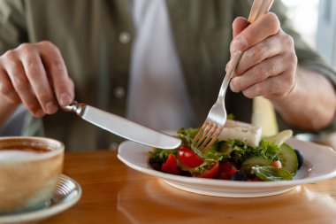Restoran masasında kapuçinoyla sağlıklı bir yemek yerken ellerinizi kapatın.