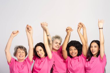 Göğüs kanseri farkındalığını desteklemek, birlik ve umudu desteklemek için pembe tişörtler giyen ve kollarını kaldıran bir grup gülümseyen kadın. Destek konsepti