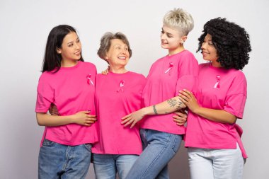 Pembe t-shirtler giyen, göğüs kanseri farkındalığını kucaklayan ve destekleyen çeşitli kadın grupları beyaz arka planda izole edilmiş pozlar veriyorlar. Destek konsepti