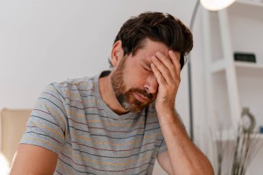 Stresli, orta yaşlı, üzgün, evde hayal kırıklığına uğramış, baş ağrısı çeken Latin bir adam. Yatak haberleri, sağlık hizmeti konsepti