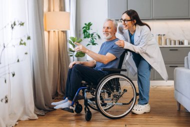 Genç hemşire, tekerlekli sandalyedeki yaşlı bir adama kapsamlı ev bakımı yardımı yapıyor, bağımsızlığı ve refahı destekliyor.