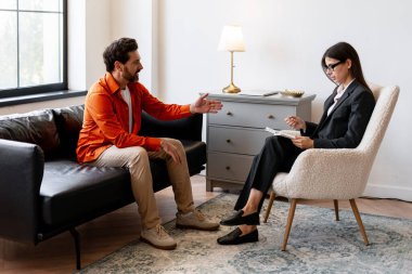 Modern ofiste oturan sakallı adam terapi sırasında kadın psikologla konuşuyor. Genç doktor hastaya danışmanlık yapıyor. Metal sağlık konsepti